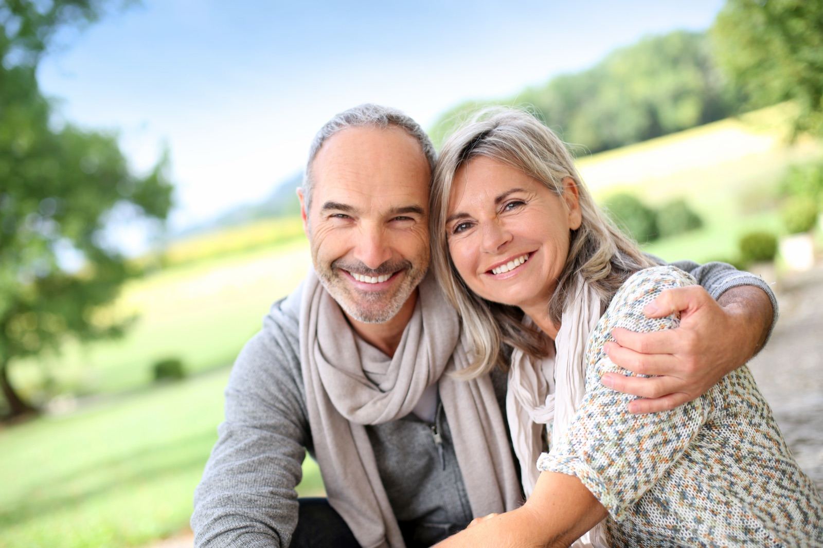 A couple in their sixties sitting together outdoors on a sunny afternoon